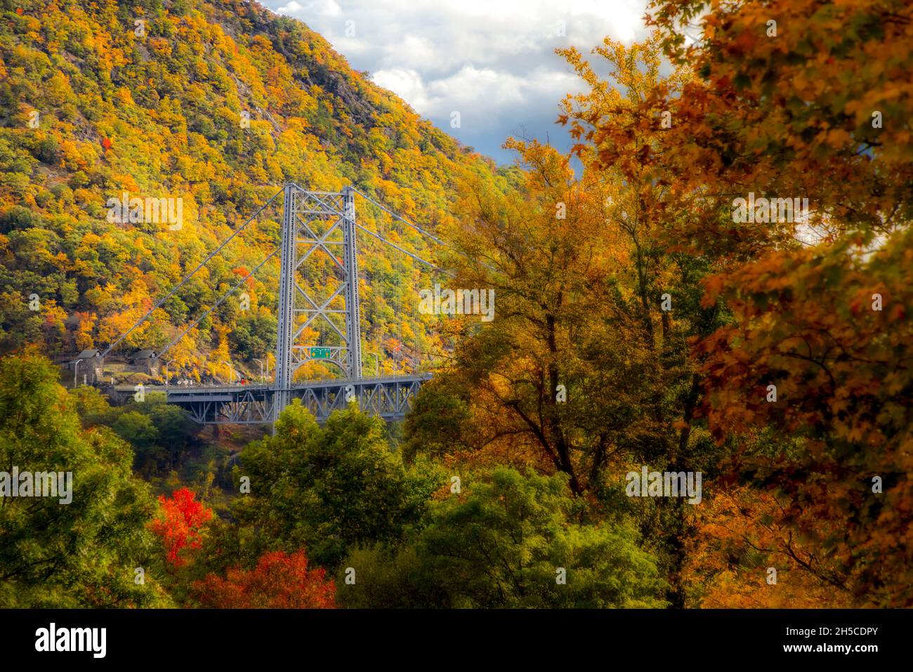 Bear Mountain Bridge Fall - Blick nach Süden auf die Bear Mountain Bridge, und die Amrican Flagge drapiert über einem der Rungen im Herbst mit seinem Magnn Stockfoto