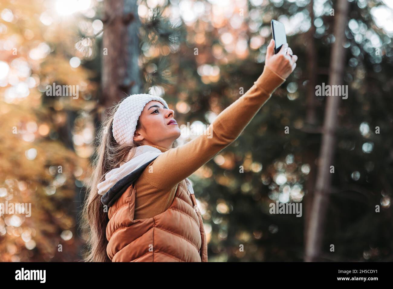 Junge, brünett weibliche Person fangen Telefonsignal im Wald Stockfoto