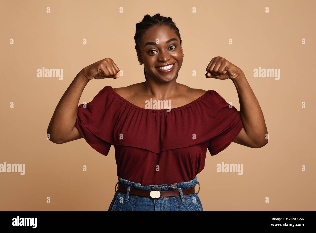 Starke afroamerikanische Frau, die ihre Muskeln abweist Stockfoto