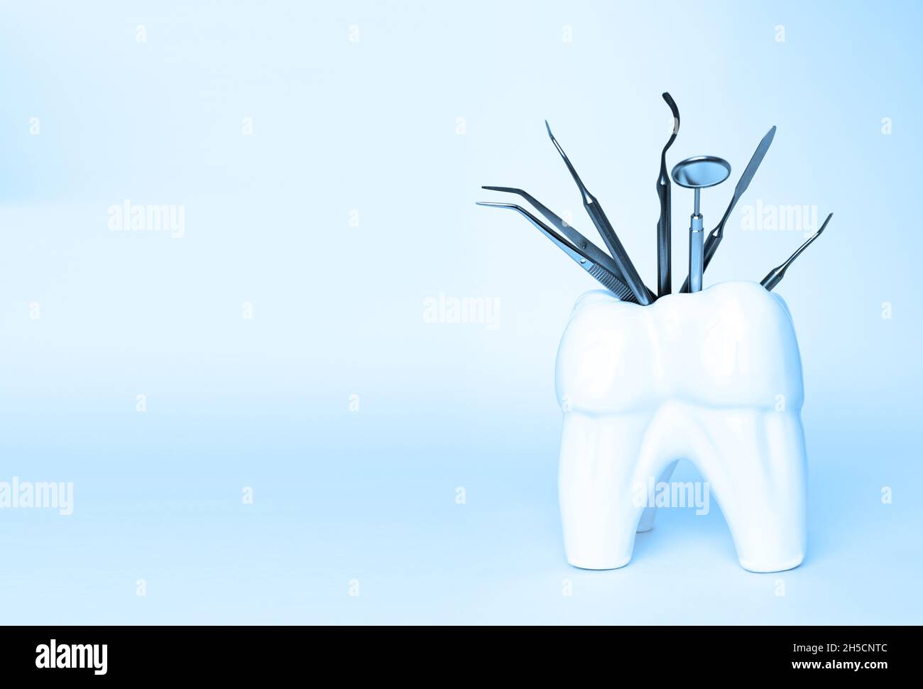 Zahnärztliche Profi-Stahlwerkzeuge in zahnförmigem Halter auf blauem Hintergrund. Set von medizinischen Geräten aus Metall für die Zahnpflege. Sichelsonde Stockfoto
