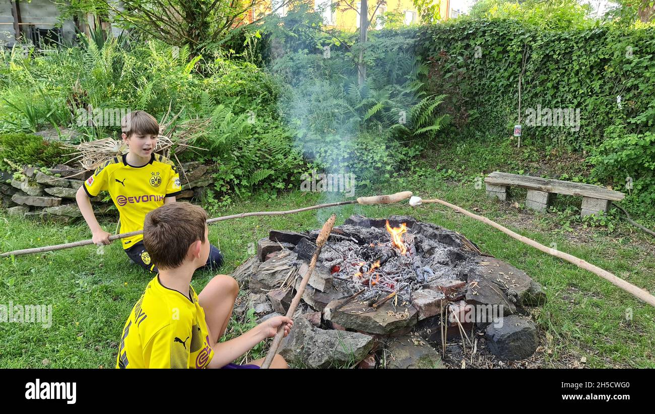 Zwei Jungen in Borussia Dortmund Trikots backen Stockbrot über einem offenen Kamin , Deutschland, Nordrhein-Westfalen, Ruhrgebiet, Dortmund Stockfoto