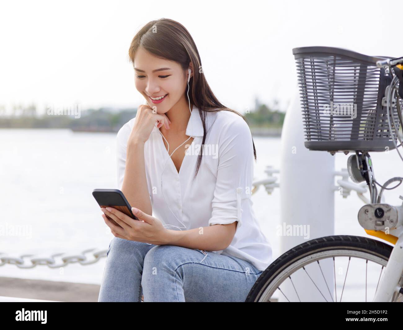 Junge Frau mit App in der Nähe der Stadt Fahrradstation.Junge Frau mit Handy für Bike-Sharing-Service. Stockfoto