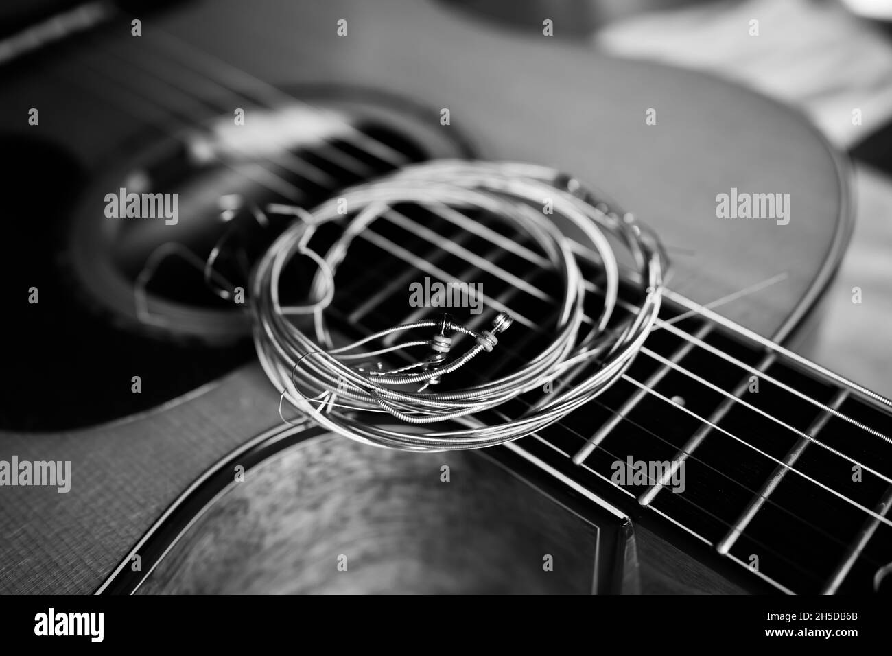 Künstlerische schwarz-weiße alte Gitarrensaite auf einer akustischen Gitarre Stockfoto