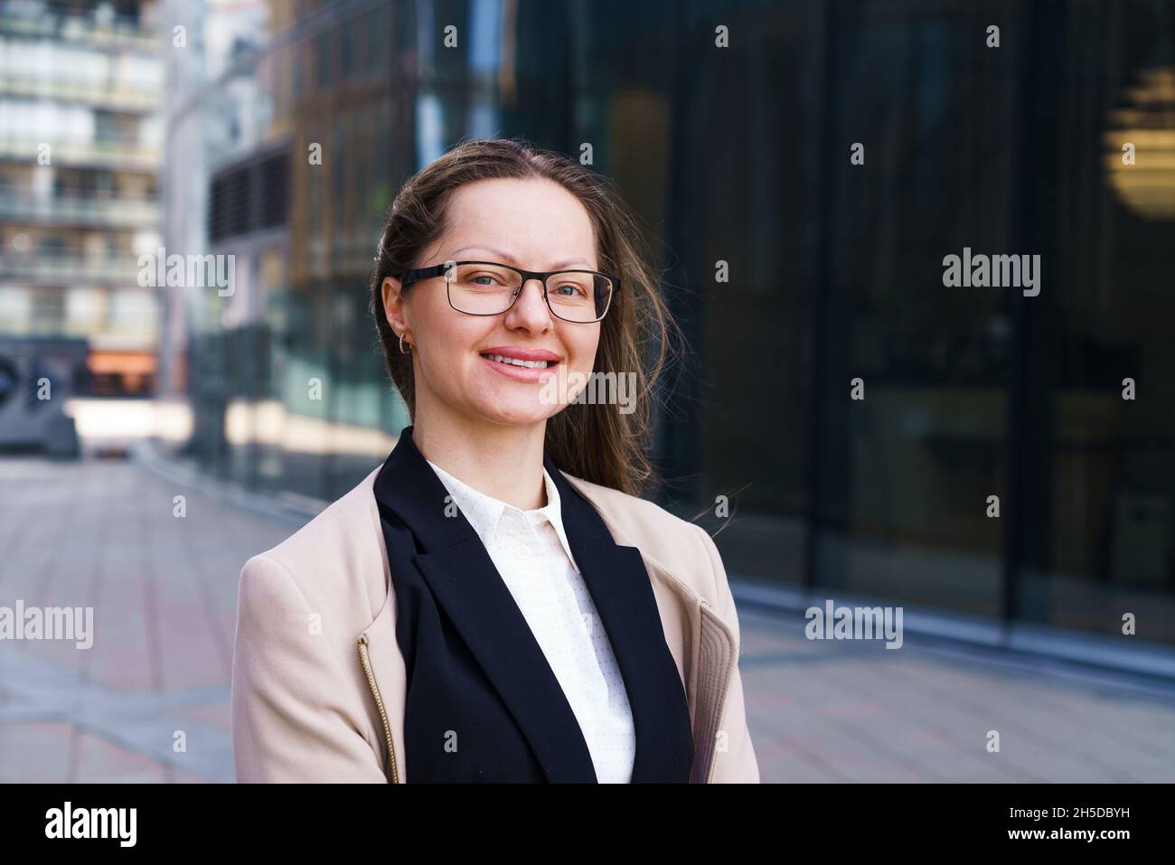 In einer Brille in der Nähe des Geschäftszentrums steht ein weibliches Porträt einer kaukasischen Geschäftsfrau in stilvoller Geschäftskleidung. Selbstbewusster und erfolgreicher Büromitarbeiter. Zielgerichteter Mädchen in einer finanziellen Angelegenheit Stockfoto