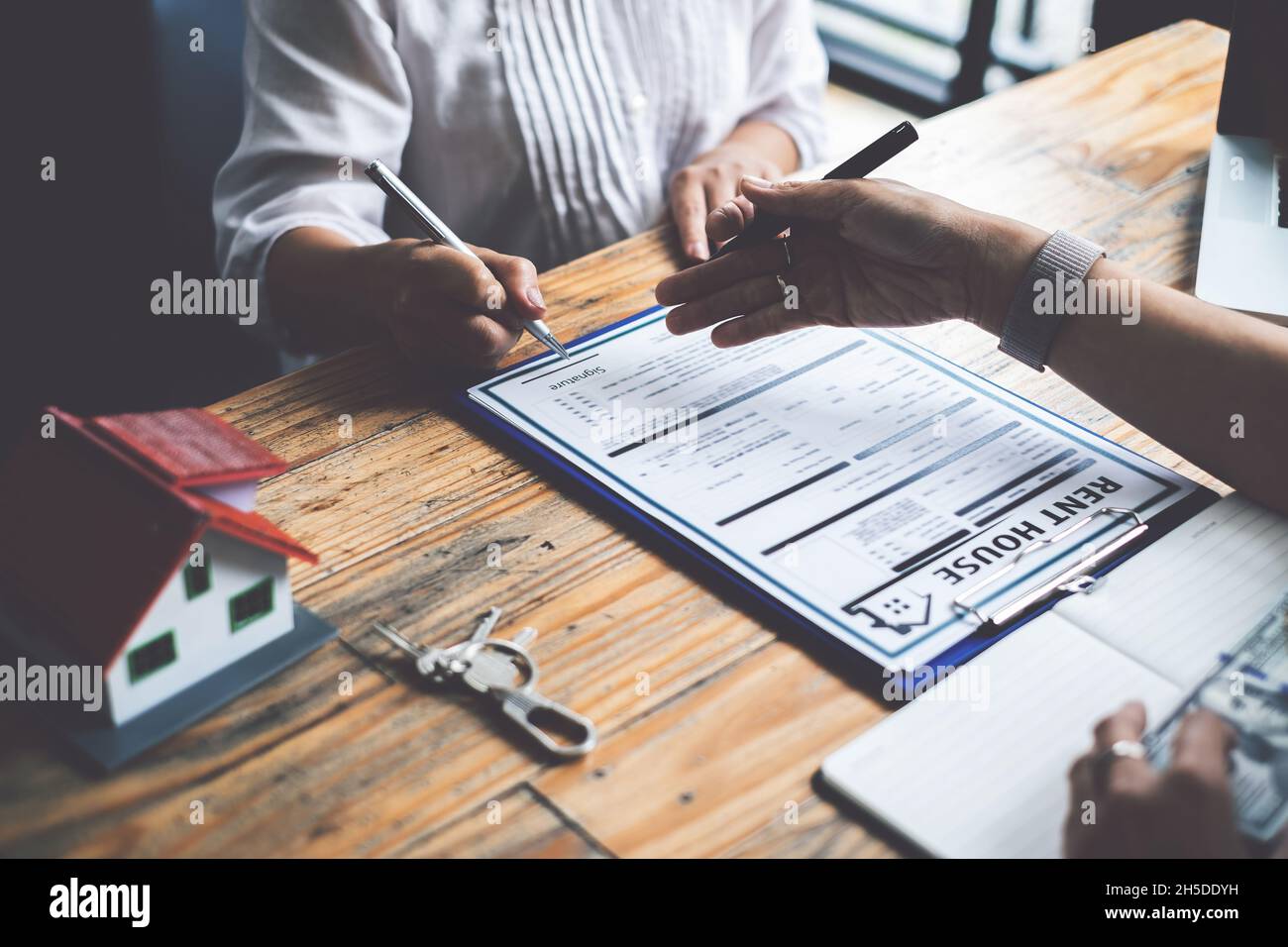 Nahaufnahme der Geschäftsfrau, die auf den Kauf eines Hauses hinweist und eine Vereinbarung unterzeichnet. Bankmanager und Immobilienkonzept Stockfoto