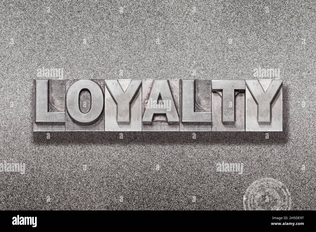 Loyalitäts-Wort aus Vintage-Buchdruck auf strukturiertem Metallic-Hintergrund Stockfoto
