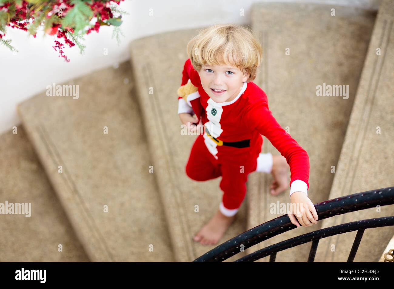 Kinder laufen Treppen am Weihnachtsmorgen. Kinder im Schlafanzug laufen nach unten, um Weihnachtsgeschenke zu öffnen. Feiern zu Hause. Familienurlaub im Winter. Stockfoto