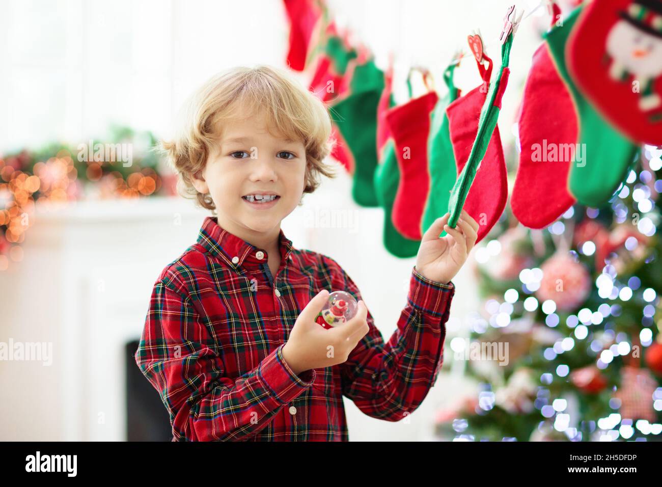 Kinder eröffnen Weihnachtsgeschenke. Kind auf der Suche nach Süßigkeiten und Geschenken im Adventskalender am Wintermorgen. Geschmückter Weihnachtsbaum Stockfoto