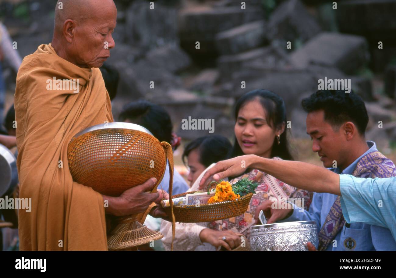 Laos: Buddhistische Mönche, die ihre täglichen Almosen am frühen Morgen im VAT Phou (Wat Phu), einem zerstörten Hindu-Tempelheiligtum Khmer (jetzt buddhistisch), in der Provinz Champasak, im Süden von Laos, durchführen. Wat Phu war ein Teil des Khmer-Reiches, das sich auf Angkor im Südwesten konzentrierte, mindestens so früh wie die Herrschaft von Yashovarman I. im frühen 10. Jahrhundert. Später wurden die ursprünglichen Gebäude ersetzt, aber einige der ursprünglichen Steinblöcke wurden wiederverwendet. Der Tempel, wie er heute steht, wurde hauptsächlich während der Koh Ker und Baphuon Perioden des 11. Jahrhunderts errichtet. Stockfoto