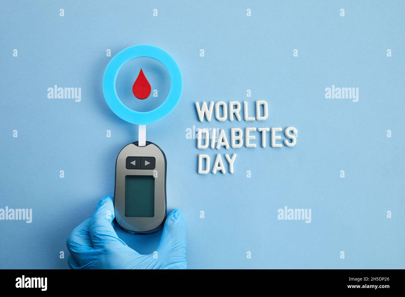 Konzept des Welt-Diabetes-Tages. Roter Blutstropfen im Kreis mit Blutzuckerteststreifen und Blutzuckermessgerät. Draufsicht Stockfoto