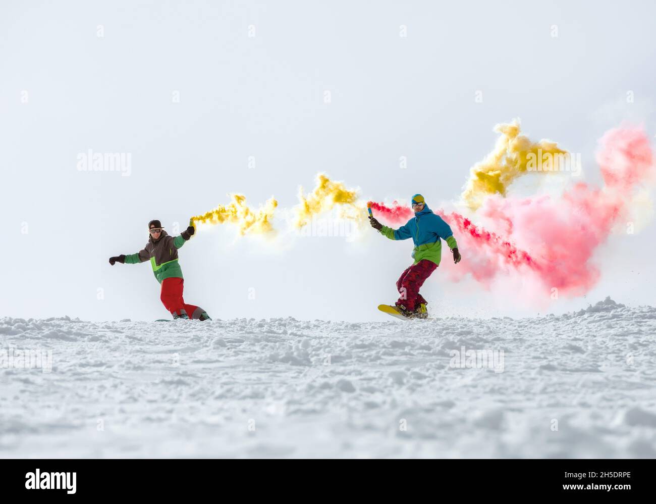 Zwei Freunde Snowboarder haben Spaß mit Rauchfackel auf der Skipiste. Wintersportkonzept Stockfoto