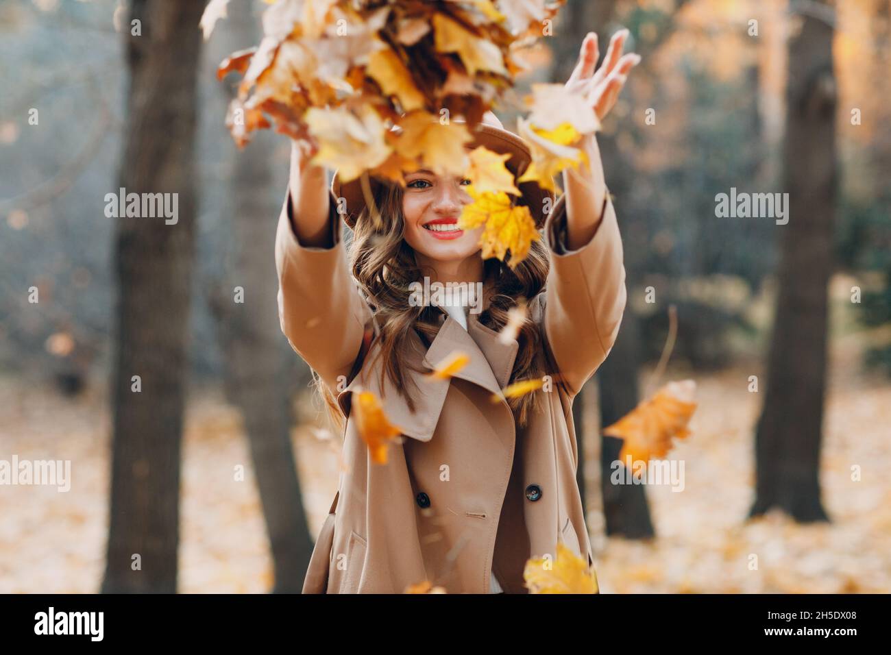 Junge Frau Modell im Herbst Park werfen gelbe Laub Ahornblätter. Herbstmode Stockfoto