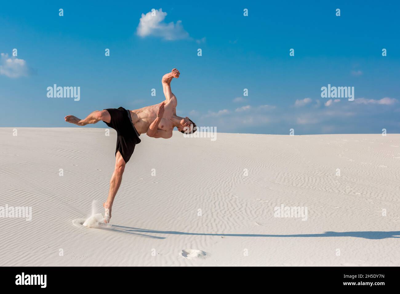 Porträt der jungen parkour Mann tun, Flip oder Salto auf dem Sand. Stockfoto