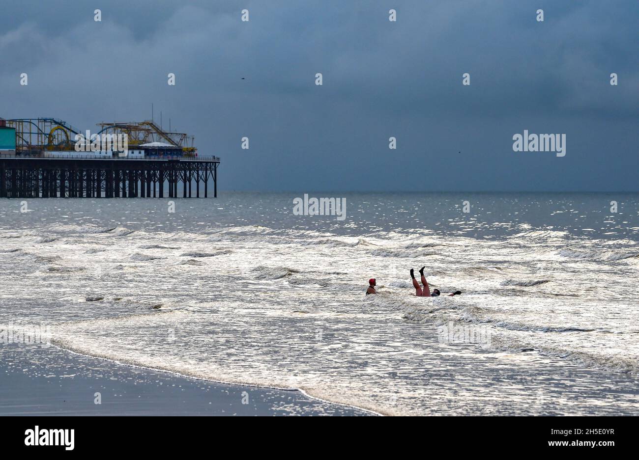 Brighton UK 19. November 2021 - Schwimmer genießen die Ebbe am Brighton Beach an einem bewölkten Morgen entlang der Südküste mit gelegentlichem Sonneneinbruch durch die dunklen Wolken : Credit Simon Dack / Alamy Live News Stockfoto