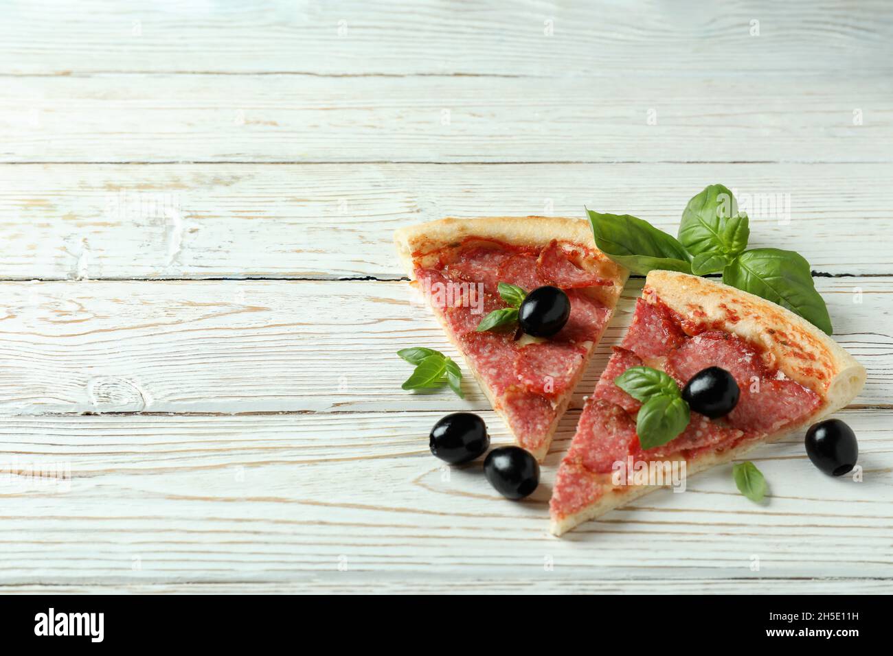 Scheiben Salami-Pizza auf weißem Holzhintergrund Stockfoto