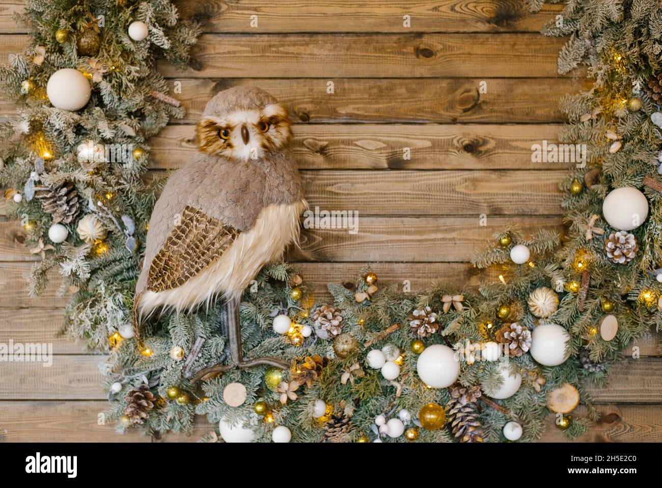 Weihnachts-Kunstkranz mit weißen und goldenen Ornamenten und einer Spielzeug-Eule Stockfoto