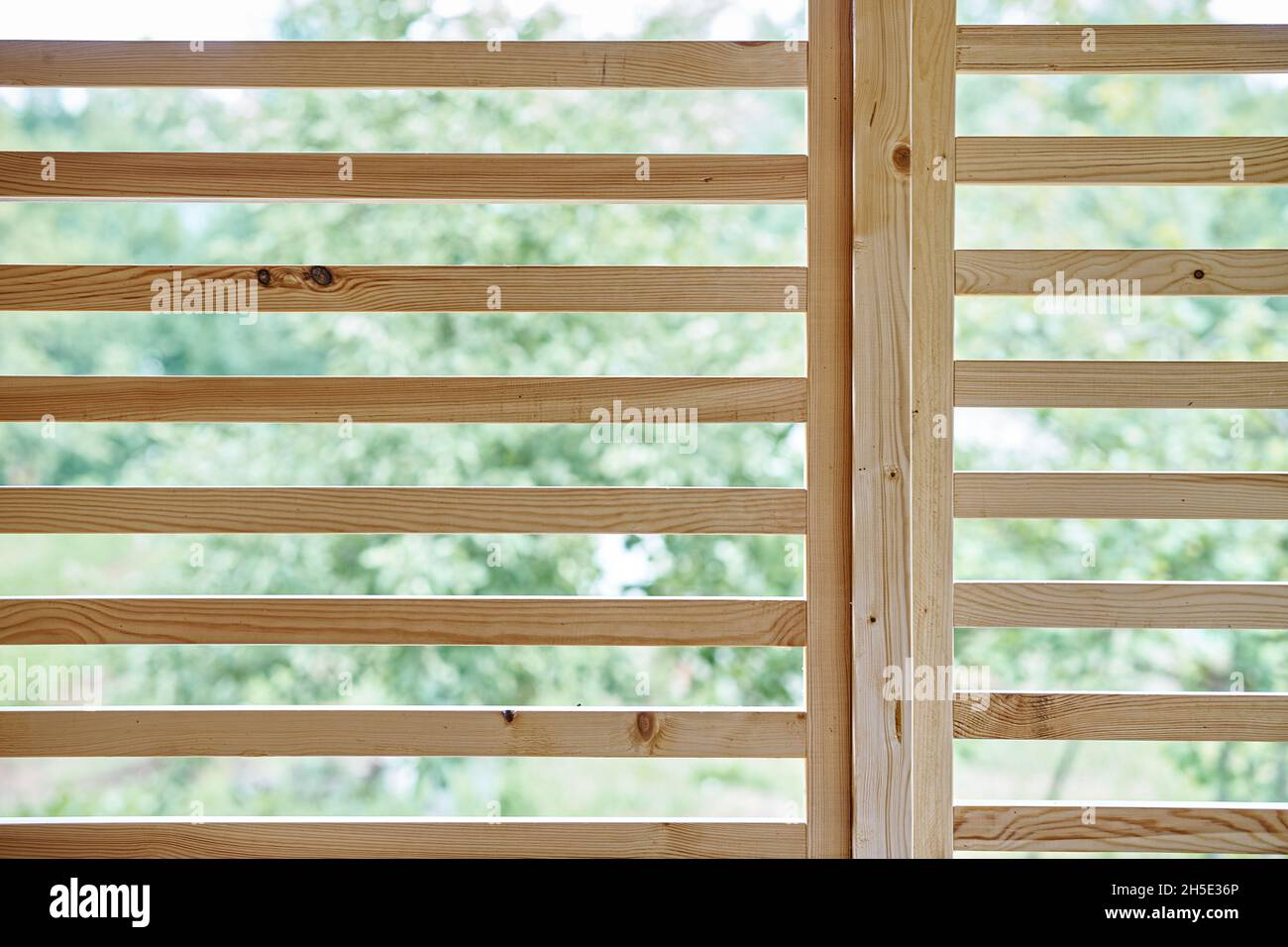 Stilvolle dekorative Trennwand aus dünnen Holzplanken steht am Frühlingstag in der Nähe auf der modernen Landhausterrasse Stockfoto