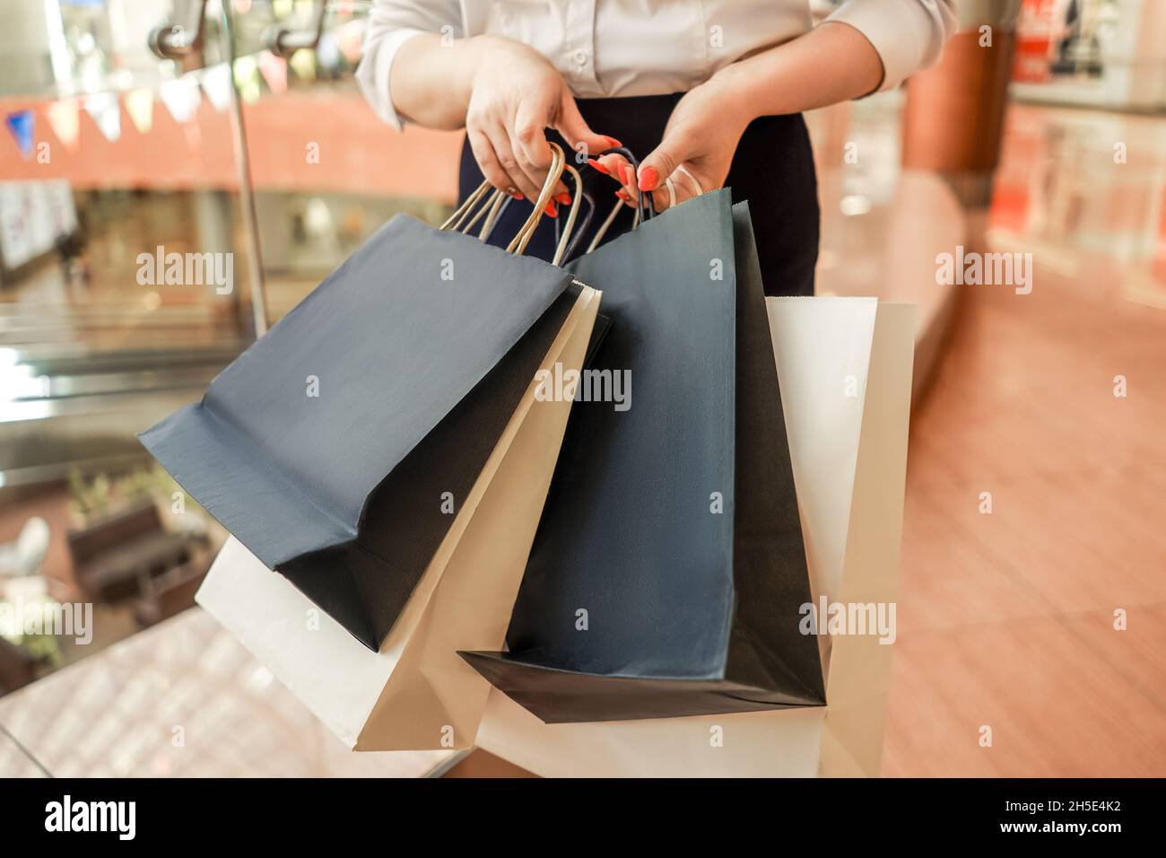 Frau mit Einkaufstaschen im Supermarkt. Ohne Kopf. Sale und Black friday Konzept. Stockfoto