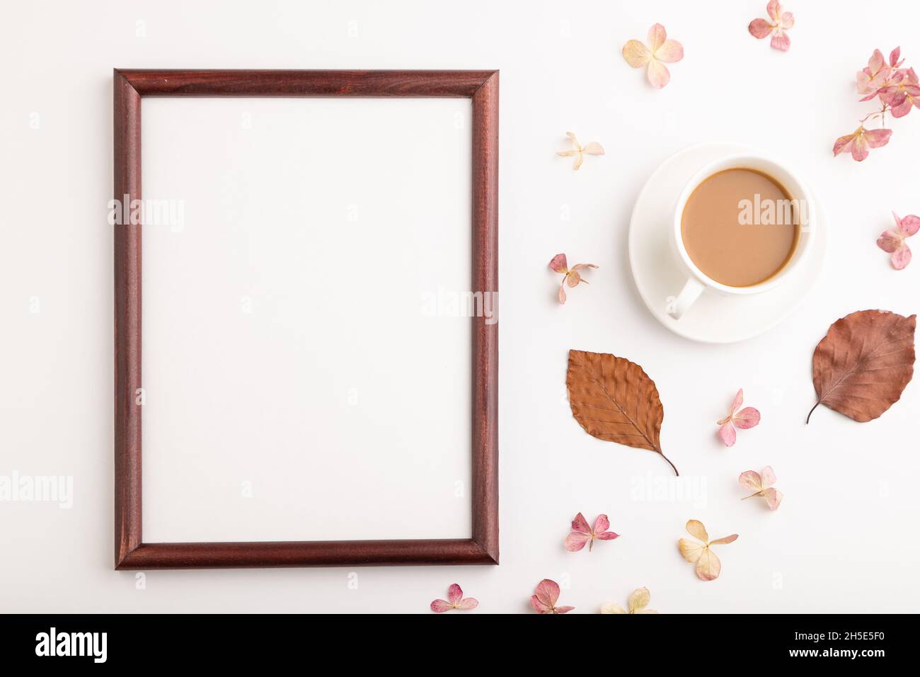 Komposition mit Holzrahmen, braunen Buchen Herbstblättern, Hortensien Blumen und Tasse Kaffee. Mockup auf weißem Hintergrund. Leer, flach liegend, Draufsicht, Stockfoto