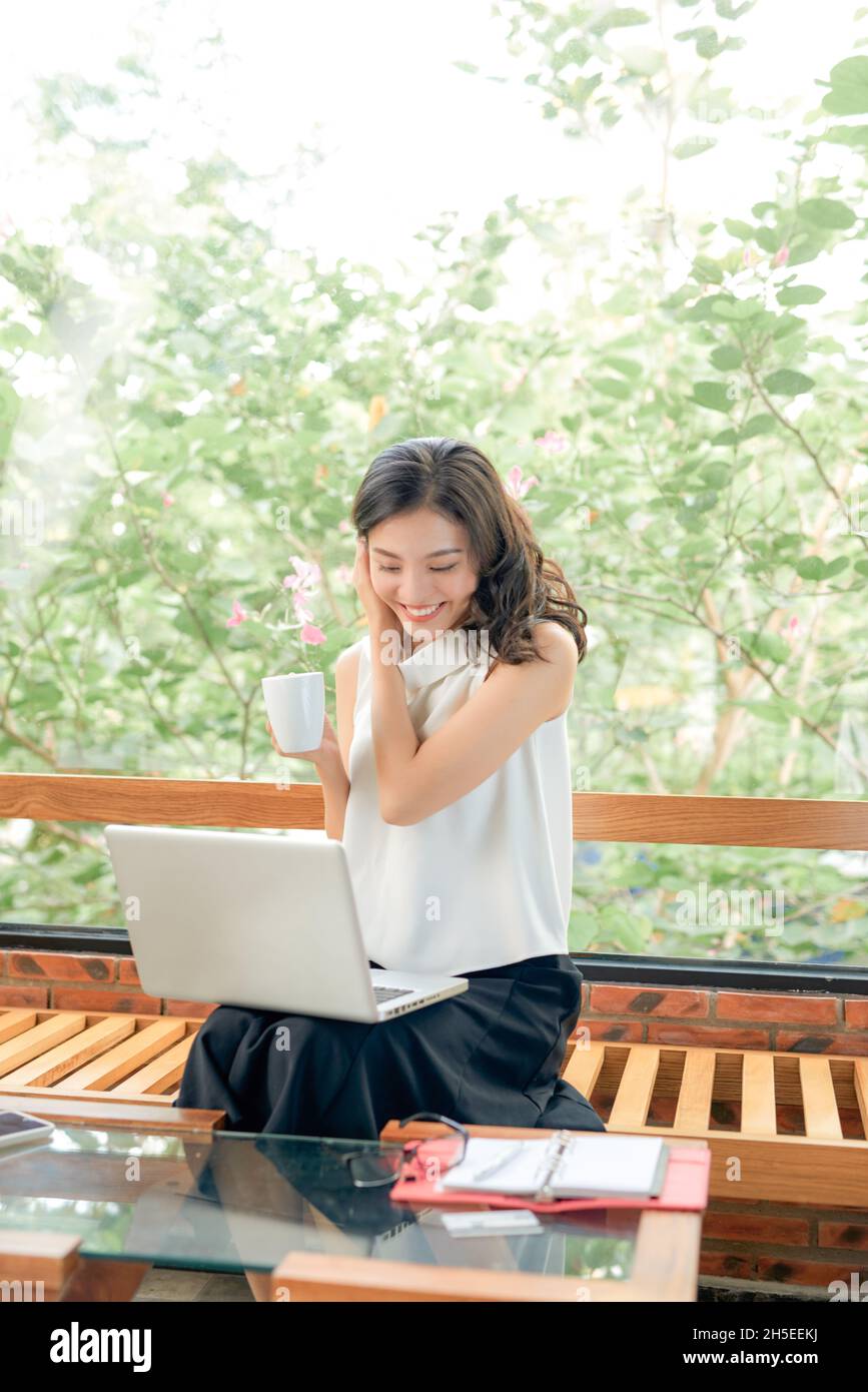 In voller Länge Porträt der fröhlichen charmanten Person sitzen halten Netbook Browsing gute Laune bei der Arbeit zu Hause drinnen Stockfoto