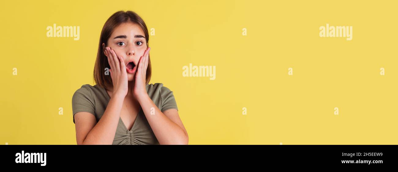 Flyer mit schockiertem jungen Mädchen, Student, der mit offenem Mund steht und isoliert auf gelbem Studiohintergrund schreit. Stockfoto