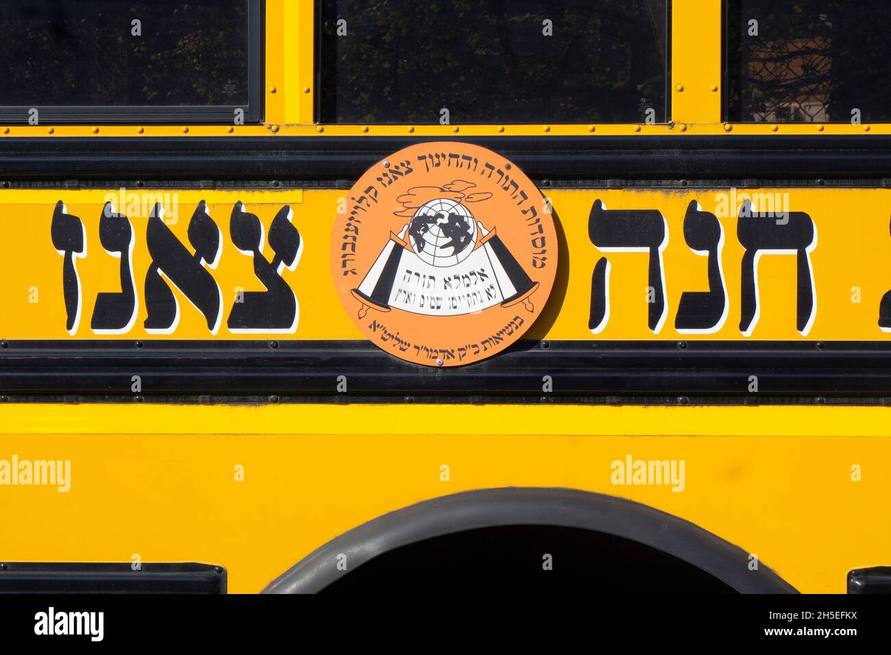 Ein Schulbus mit hebräischem Logo für die jüdische Gruppe Sanz Klausenburg mit chassidischem Namen. In Williamsburg, Brooklyn, New York City. Stockfoto