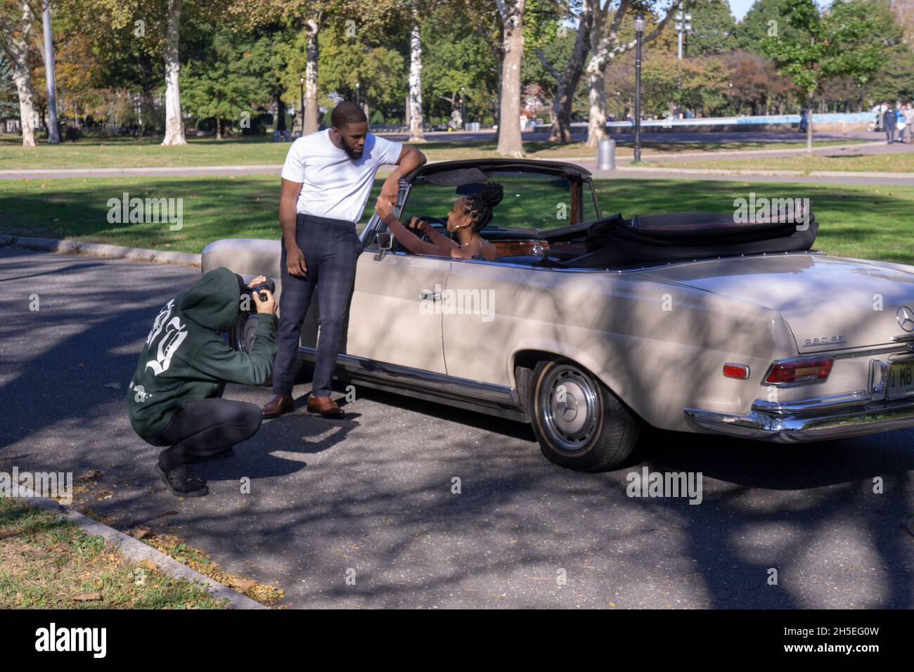 Ein Fotoshooting mit einem Model, Musiker, Fotograf und Mercedes Benz Cabrio in einem Park in Queens, New York City. Stockfoto