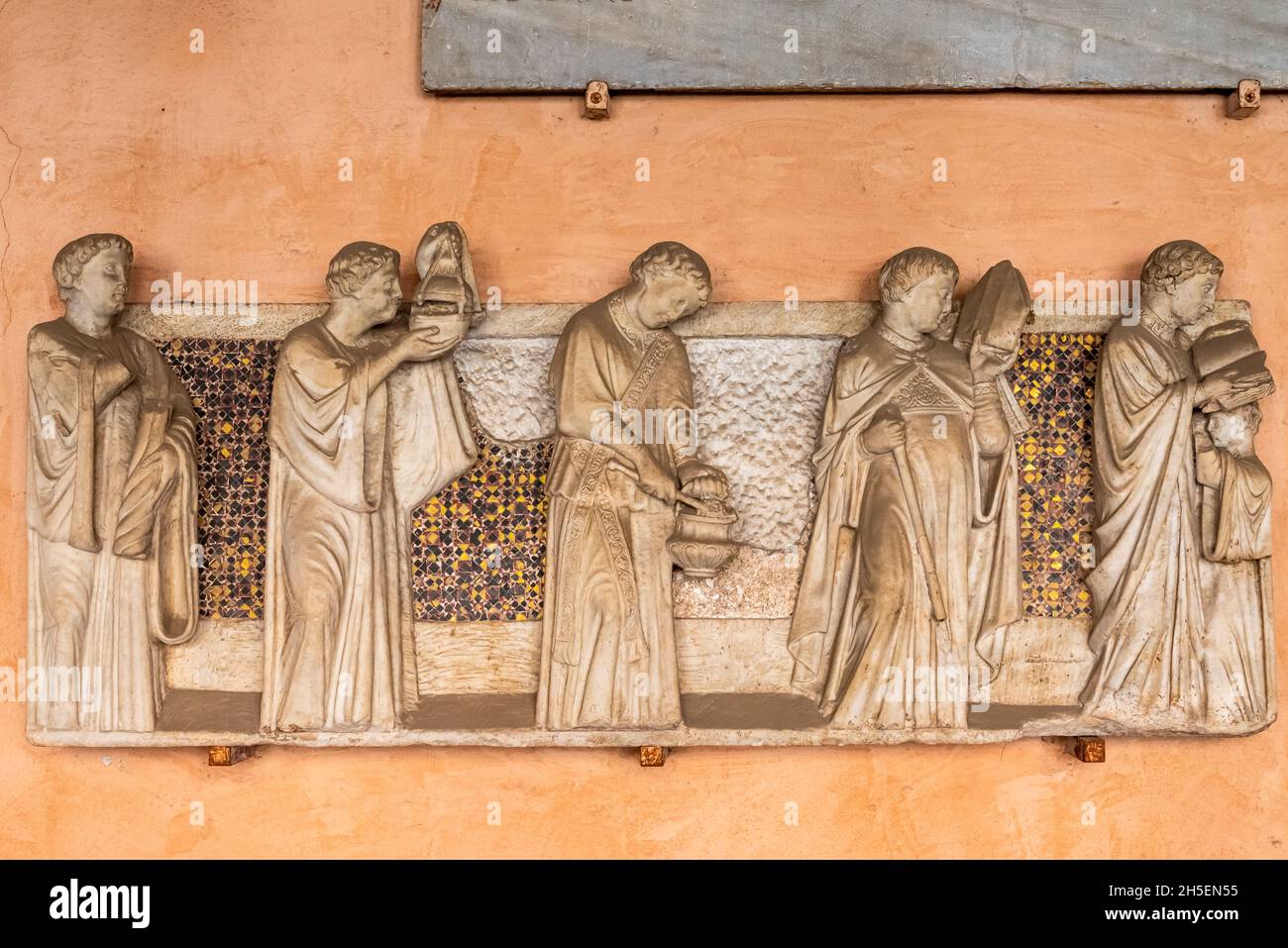 Mittelalterliche Marmorskulpturen, die in einem italienischen Kloster an einer Wand geschnitzt wurden und eine Gruppe katholischer Mönche darstellen Stockfoto