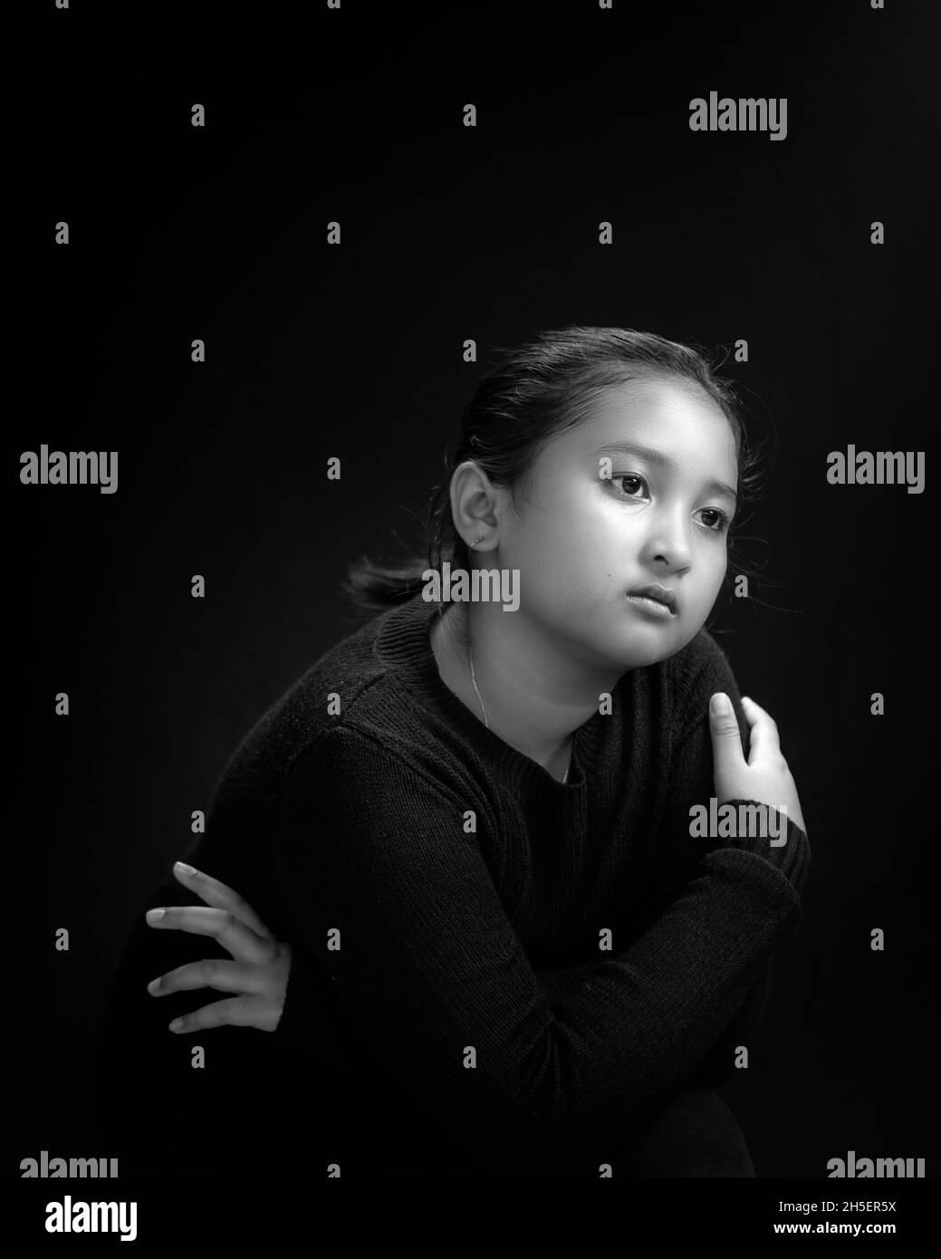 Mädchen trägt schwarzes Hemd und schwarzen Hintergrund in Schwarz & Weiß Porträt Stockfoto
