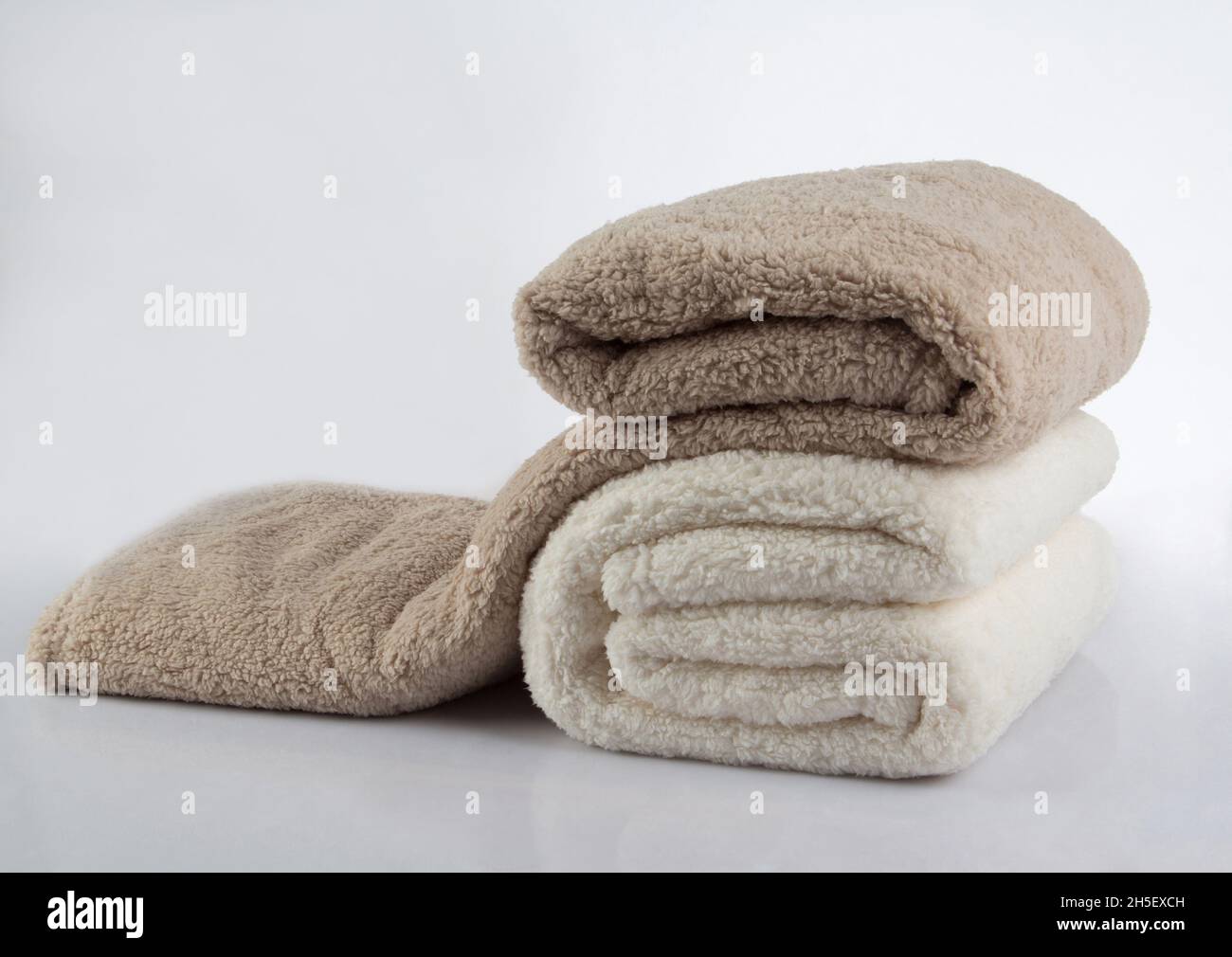 Weicher und warmer Stapel gefalteter Decken, isoliert auf weißem Hintergrund Stockfoto