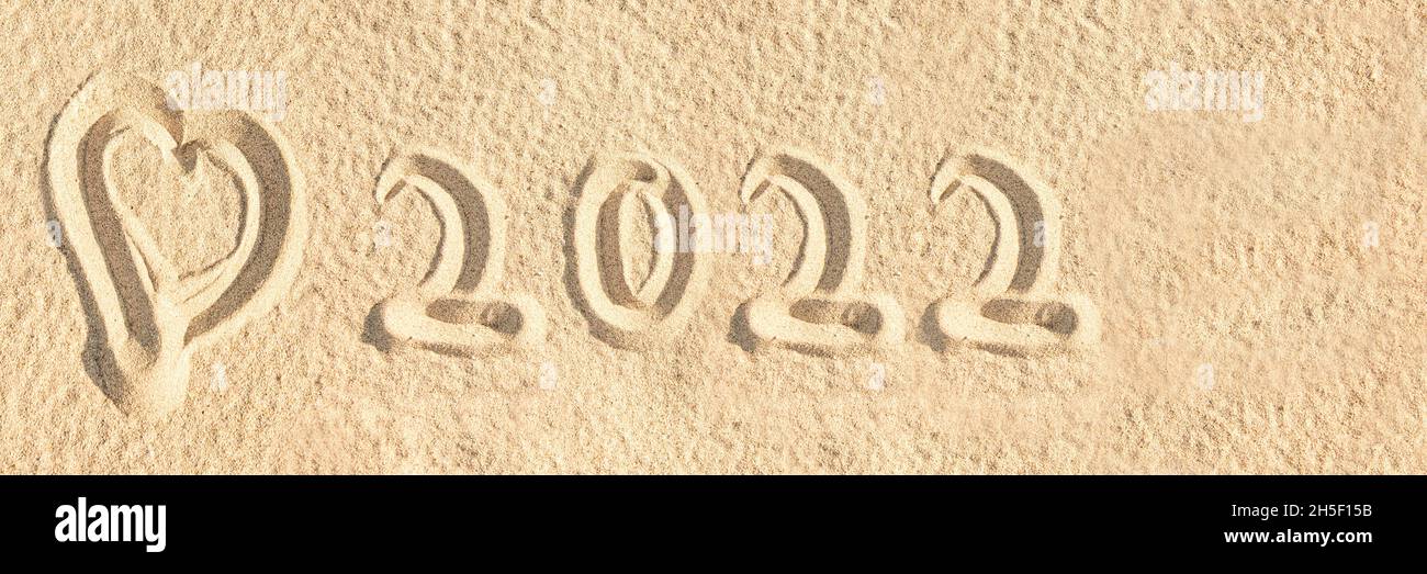 2022 geschrieben in den Sand eines Strandes mit einem Herz, Neujahr travl Web Banner Stockfoto