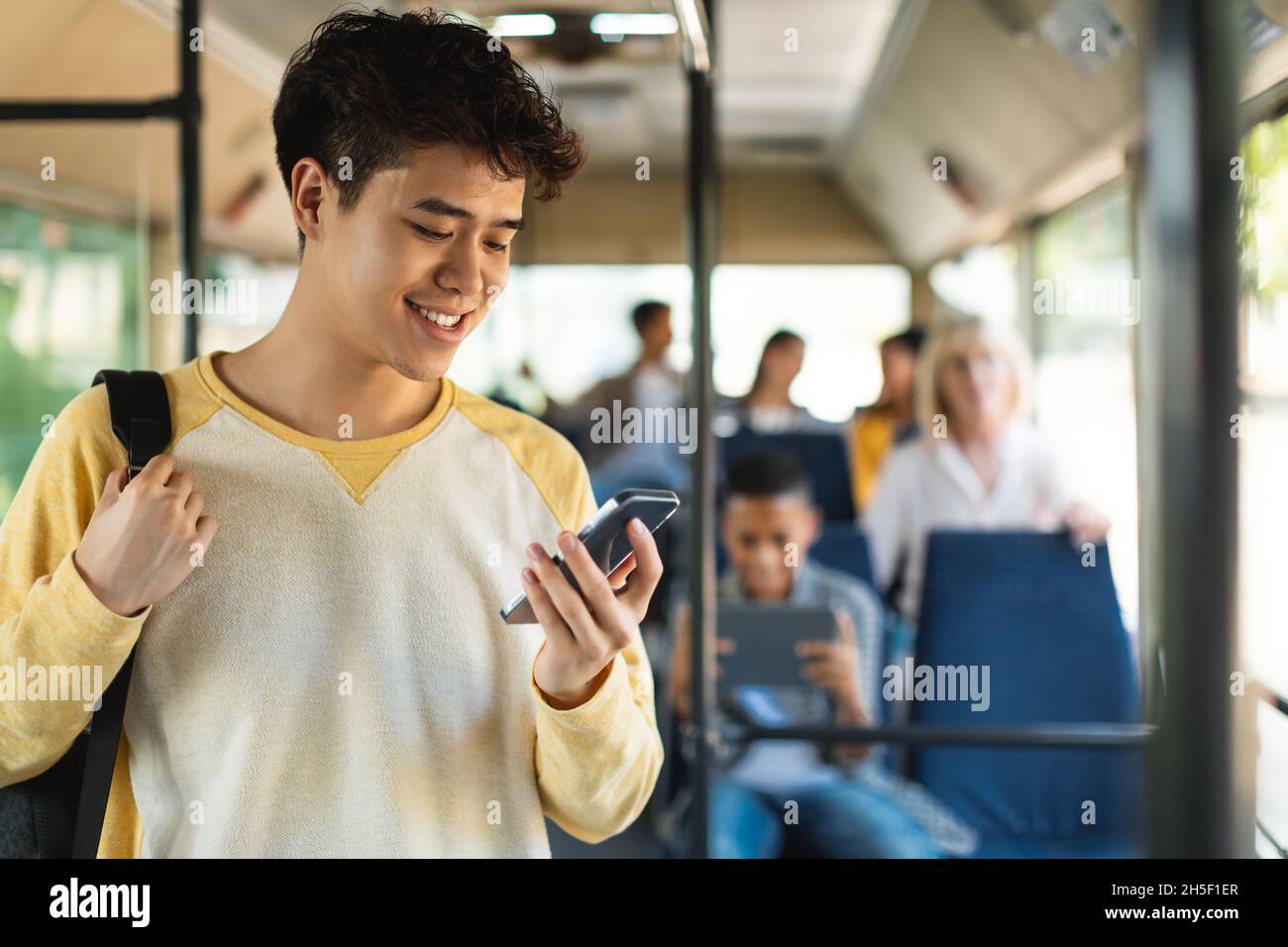 Haapy Asian Kerl mit Handy im Bus Stockfoto