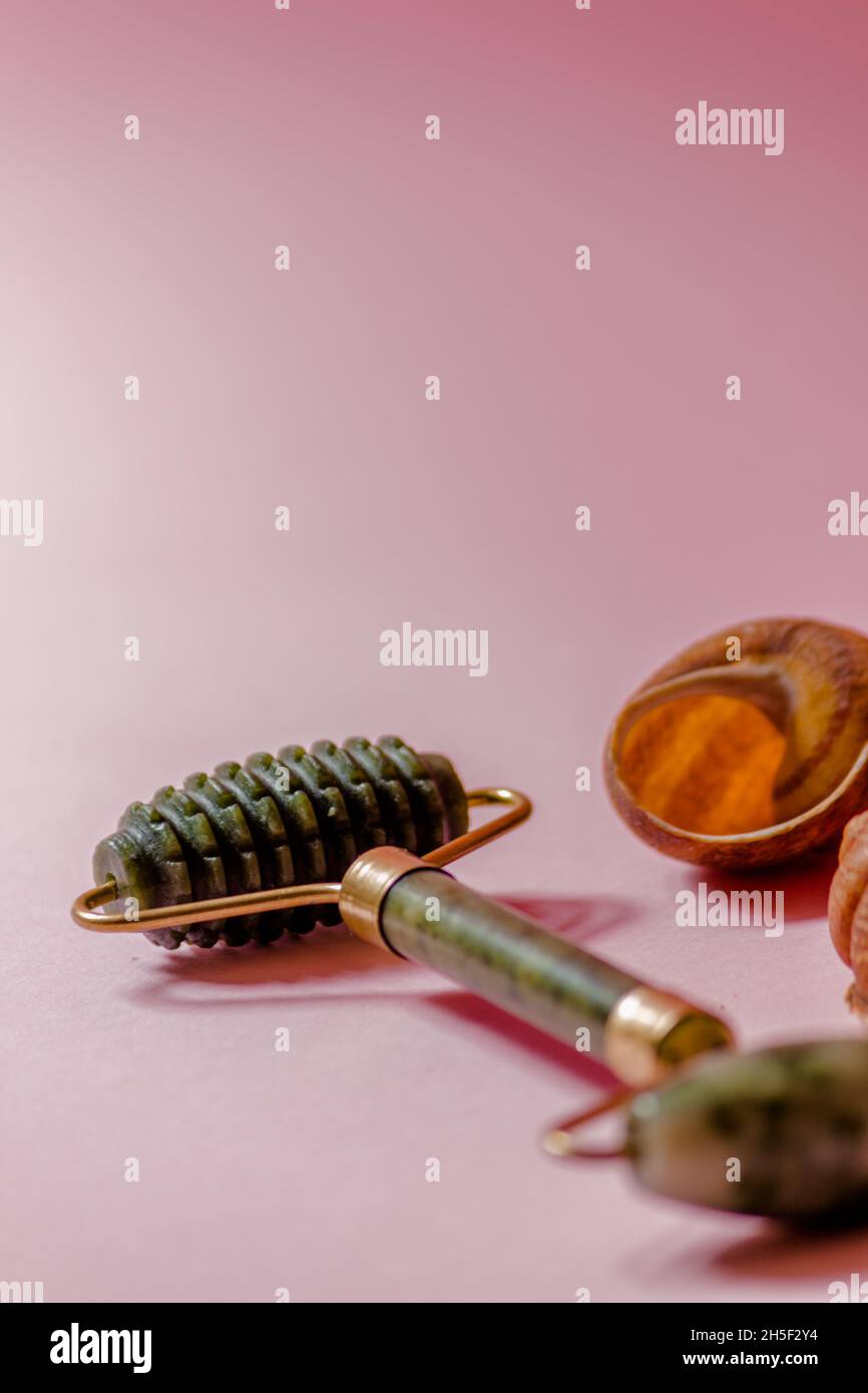 Jade-Scruber-Massagegerät und Rollergesichtsmassager auf rosa Hintergrund. Stockfoto
