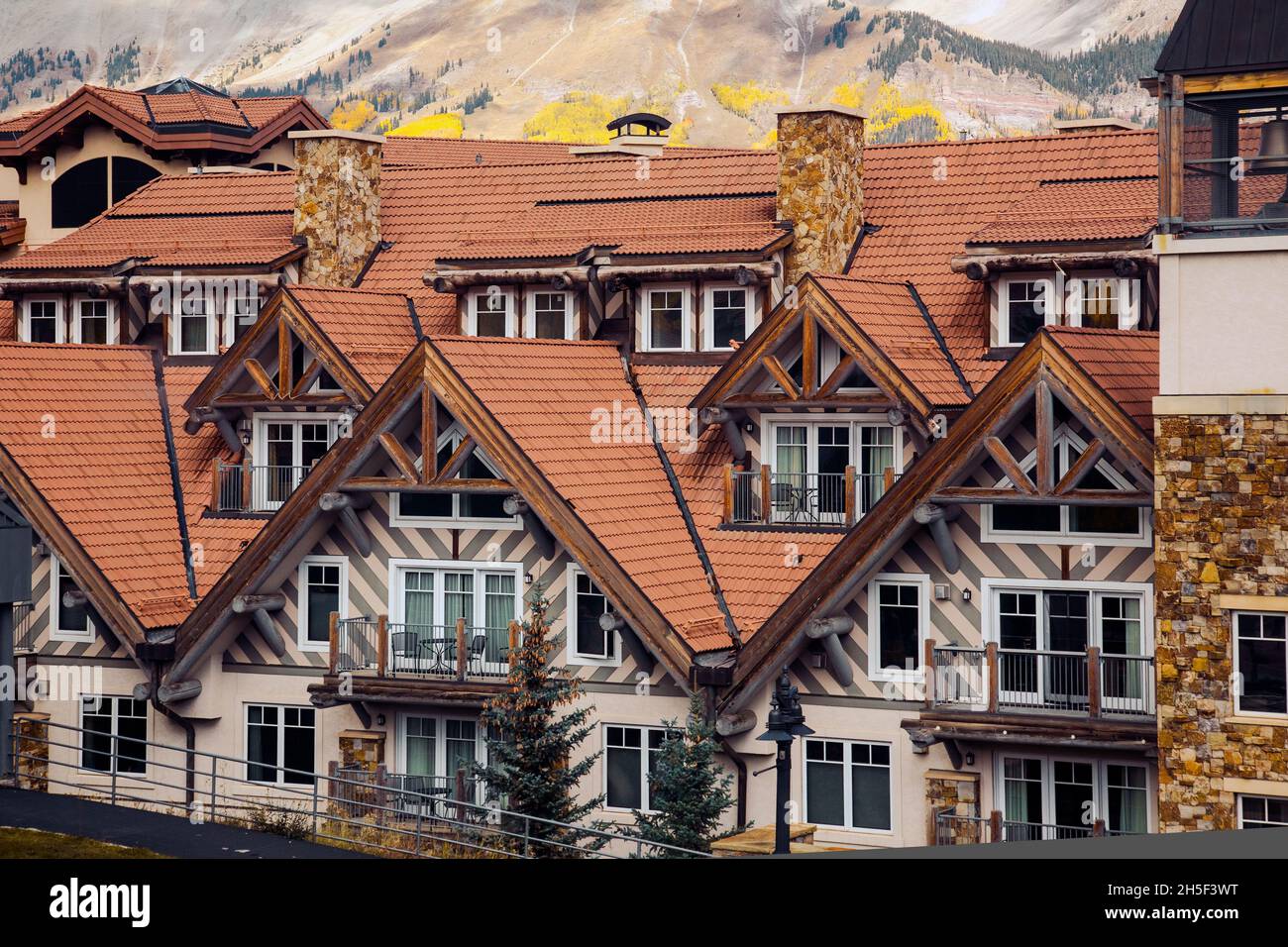 Rote Ziegeldächer mit Schornsteinen moderner Häuser mit Glasfenstern und Balkonen Stockfoto