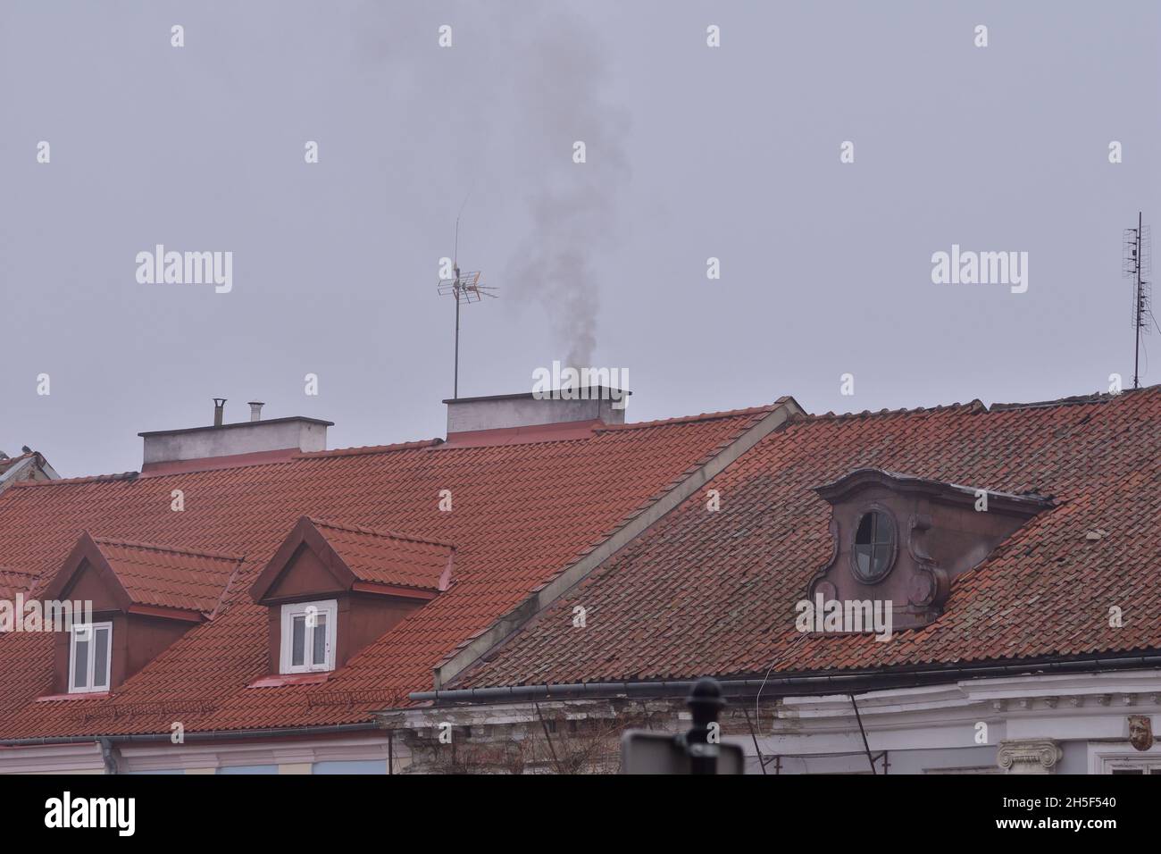 Der Rauch aus dem Kamin eines Kohleofens in einem alten Gebäude an einem düsteren Herbsttag. Stockfoto