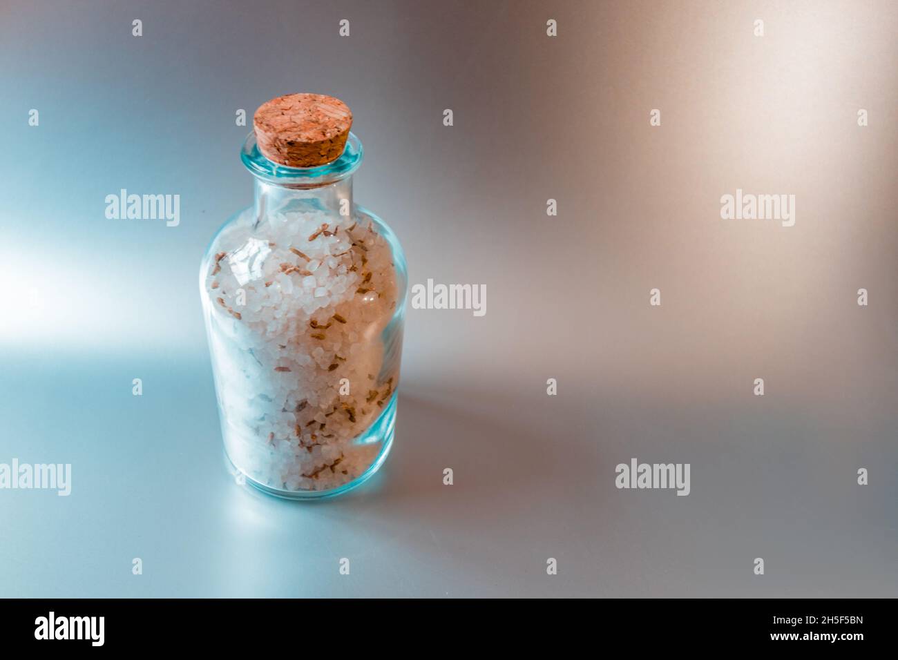 Ein Glasbehälter mit Meersalz steht vor einem hellen Küchenhintergrund. Stockfoto