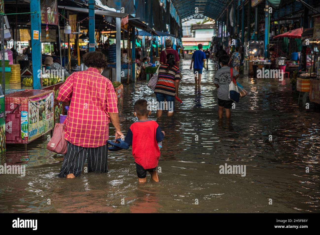 Samut Prakarn, Thailand. November 2021. Während einer Sturzflut auf dem Pak Nam Frischemarkt in Samut Prakan waten Menschen durch eine überflutete Straße.Blitzfluten ereigneten sich in vielen niedrig gelegenen Gebieten neben dem Chao Phraya Fluss in Bangkok und nahe gelegenen Provinzen wie Samut Prakan in Nonthaburi aufgrund starker Regenfälle. Kredit: SOPA Images Limited/Alamy Live Nachrichten Stockfoto