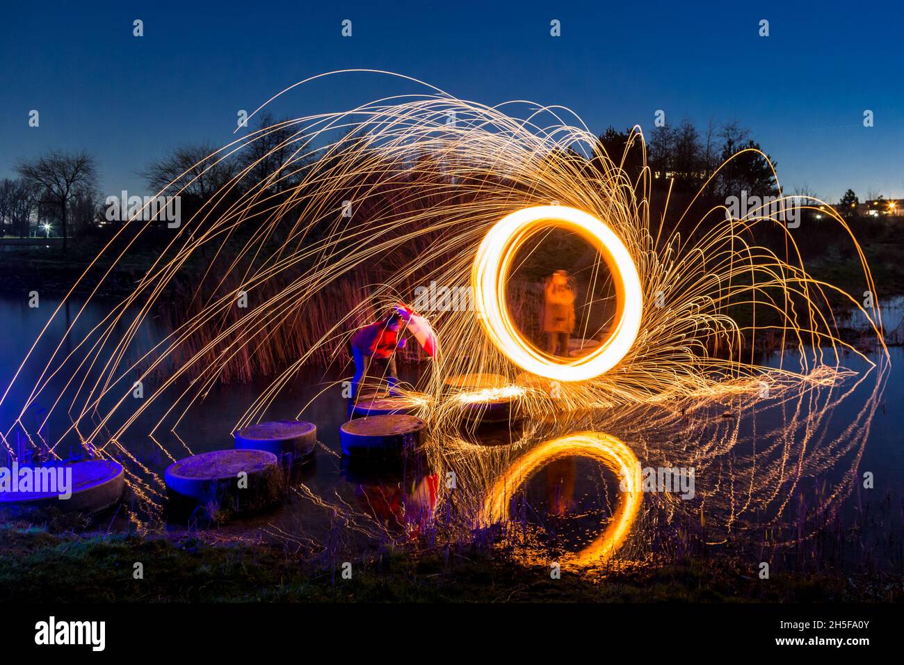 Leichte Malerei mit Stahlwolle; pyrotechnische Ausstellung bei Nacht. Es regnet Licht über dem Regenschirm. Stockfoto