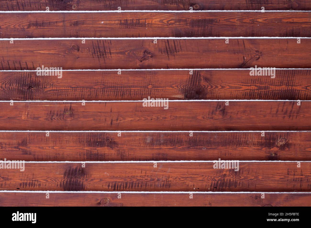 Holzzaunhintergrund mit auf den Bretter liegendem Schnee Stockfoto