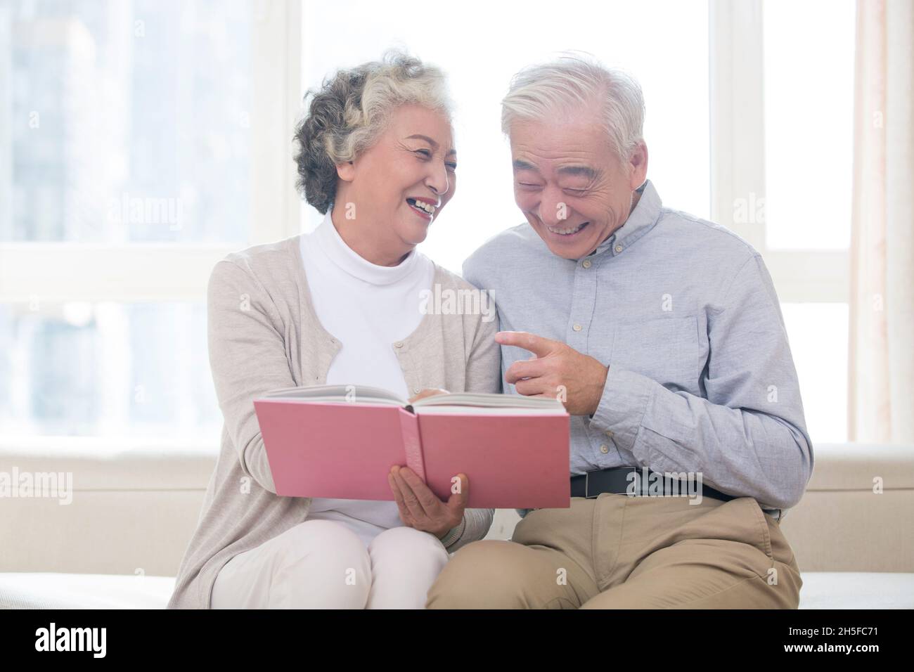 Glückliches altes Paar, das zusammen das Fotoalbum anschaut Stockfoto