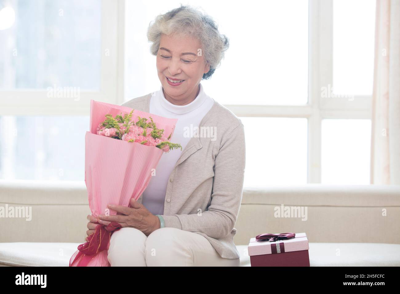 Alte Frau, die Blumen in der Hand hält Stockfoto