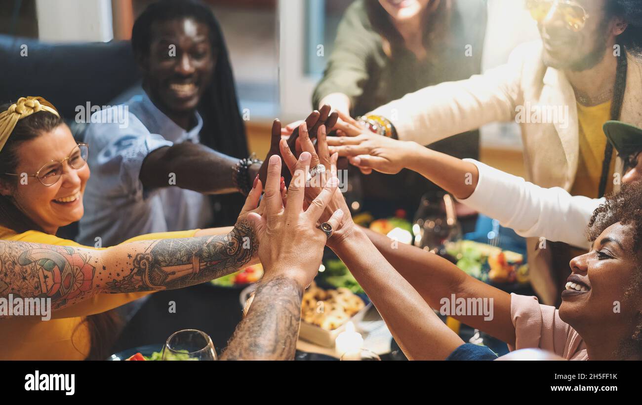 Vielfältige Gruppe von Menschen, die sich die Hände verbinden, sitzen am Esstisch aus nächster Nähe - Multi-ethnische Gruppe von Freunden, die Spaß haben, kooperieren - Konzept des succ Stockfoto