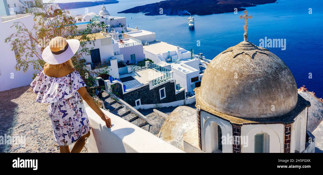 Frau in elegantem Kleid, die wunderschöne Meereslandschaft von den Straßen Santorinis genießt Stockfoto