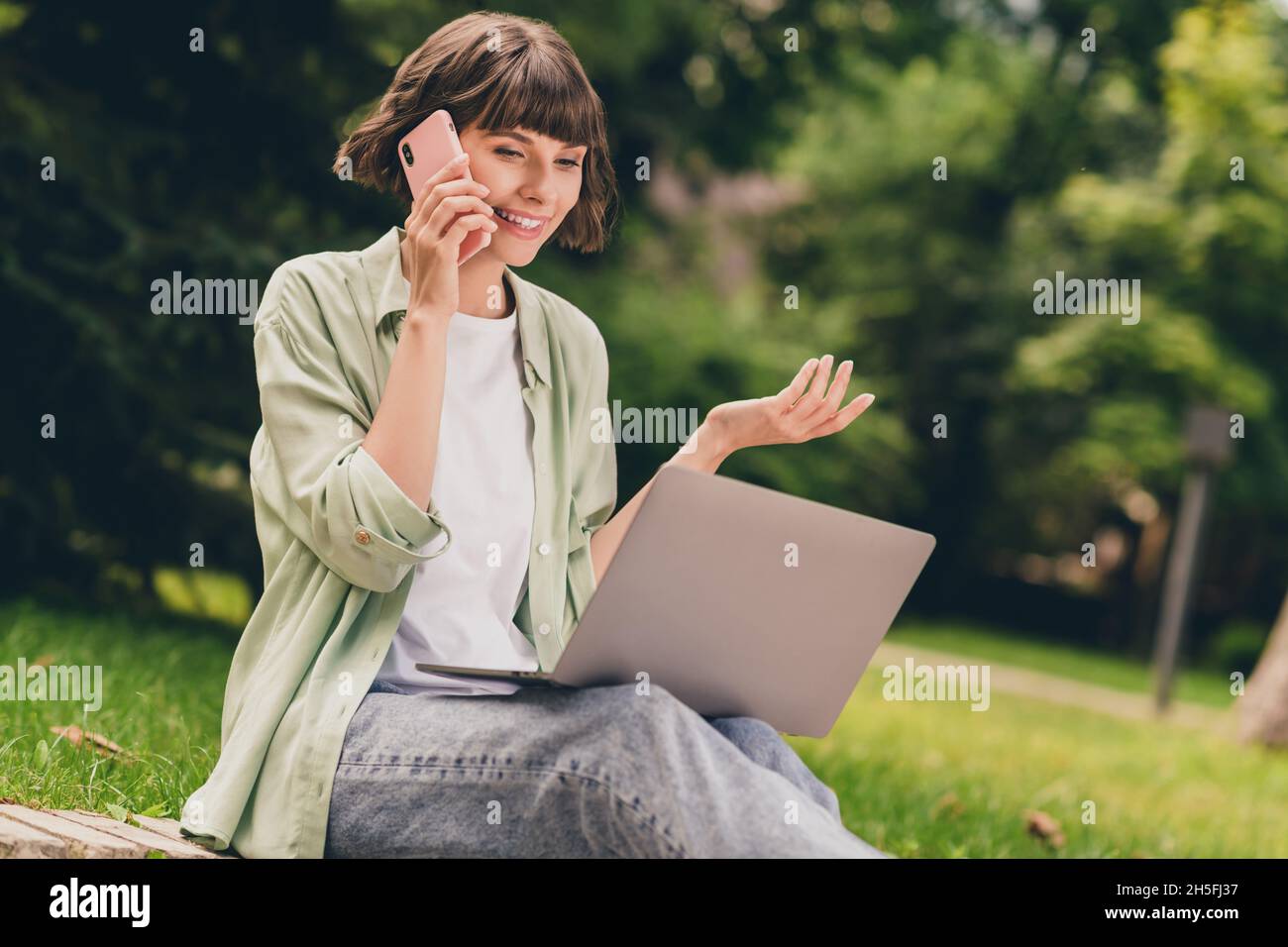 Portrait Foto lächelnd junges Mädchen auf dem Boden sitzen Arbeit auf Laptop Surfen im Internet auf dem Handy reden Stockfoto