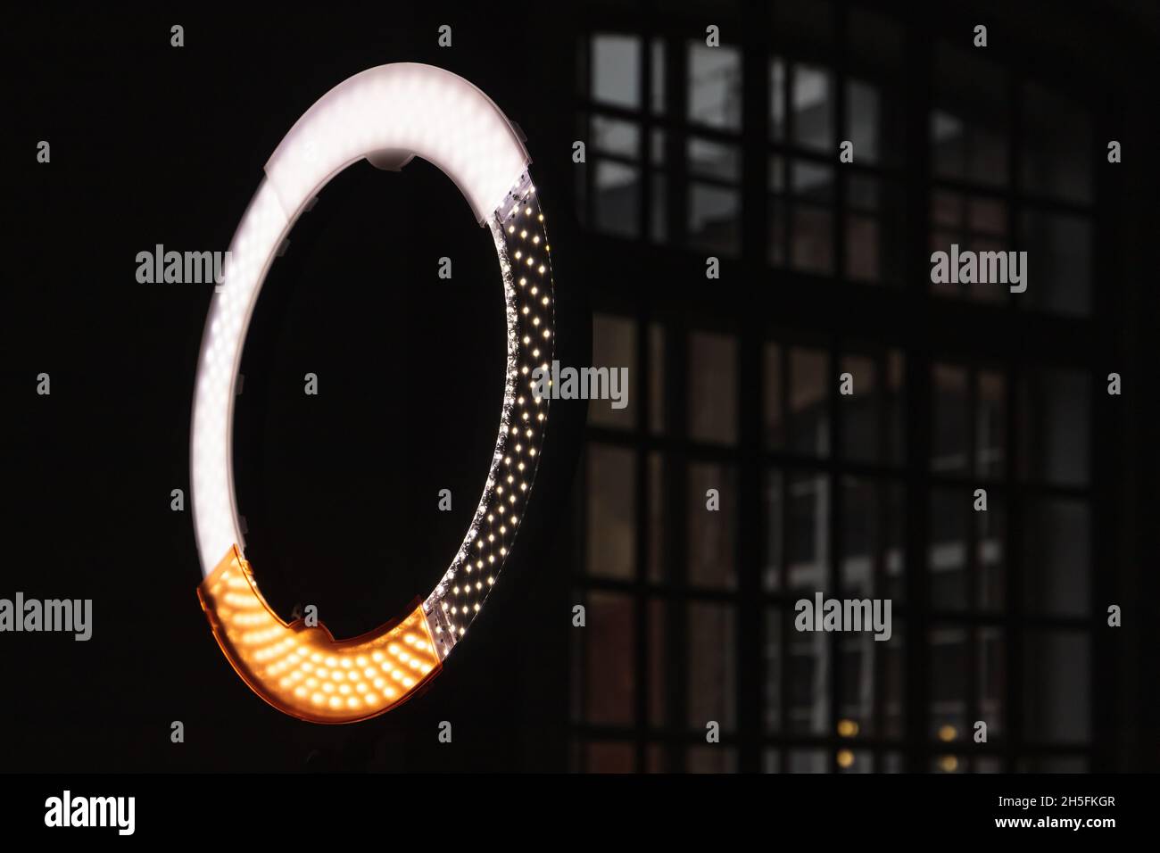 Kreisförmiges LED-Licht, das im dunklen Fotostudio leuchtet, Nahaufnahme mit selektivem Fokus Stockfoto