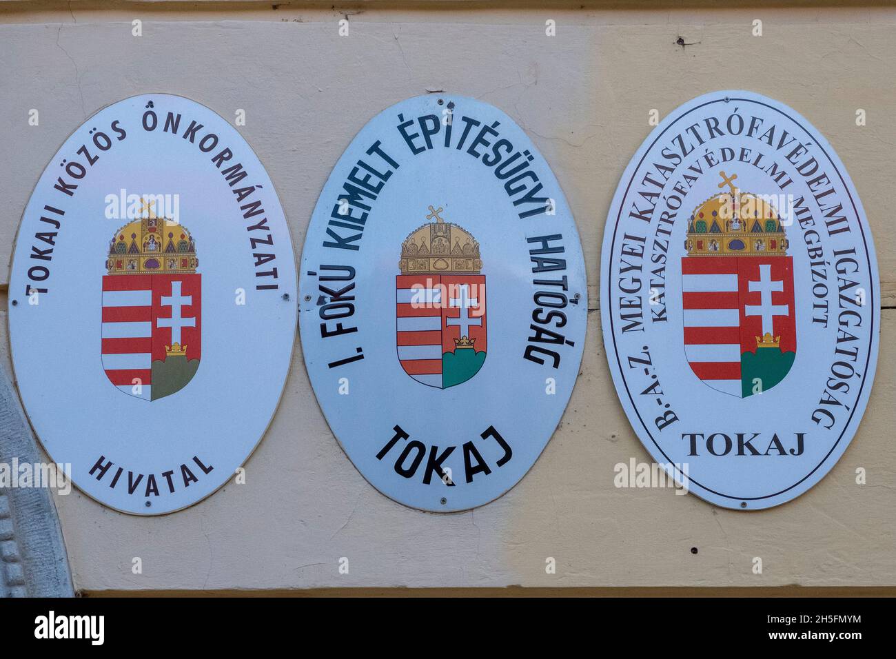 Plaketten der lokalen und regionalen Verwaltung an der Wand des Regierungsgebäudes im Zentrum von Tokaj, Ungarn Stockfoto