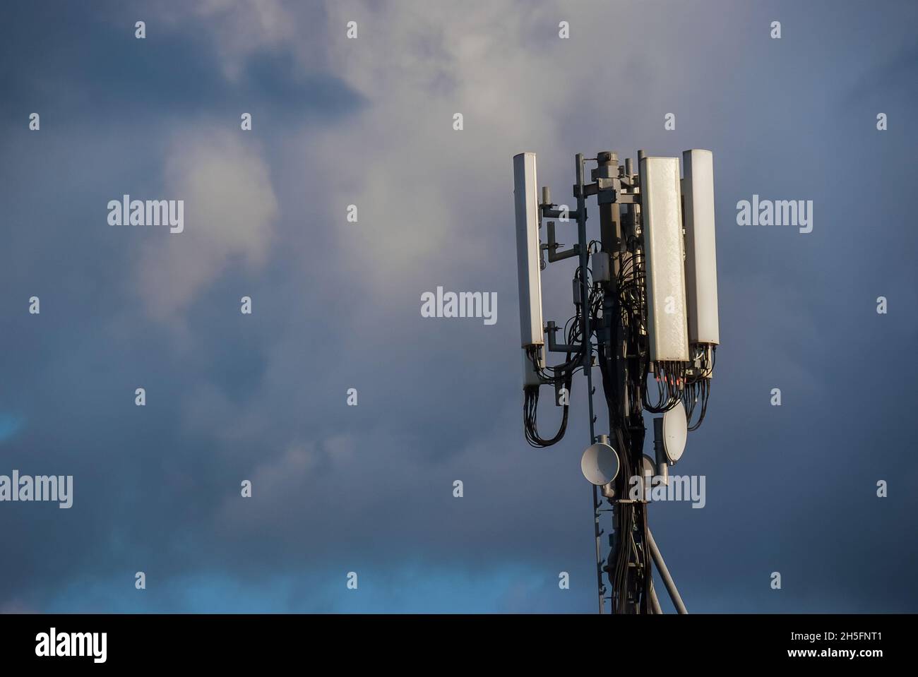 Elektromagnetische Strahlung. Telekommunikationsturm mit 5G- und 4G-Antennen zwischen den Wolken (mit Kopierplatz) Stockfoto