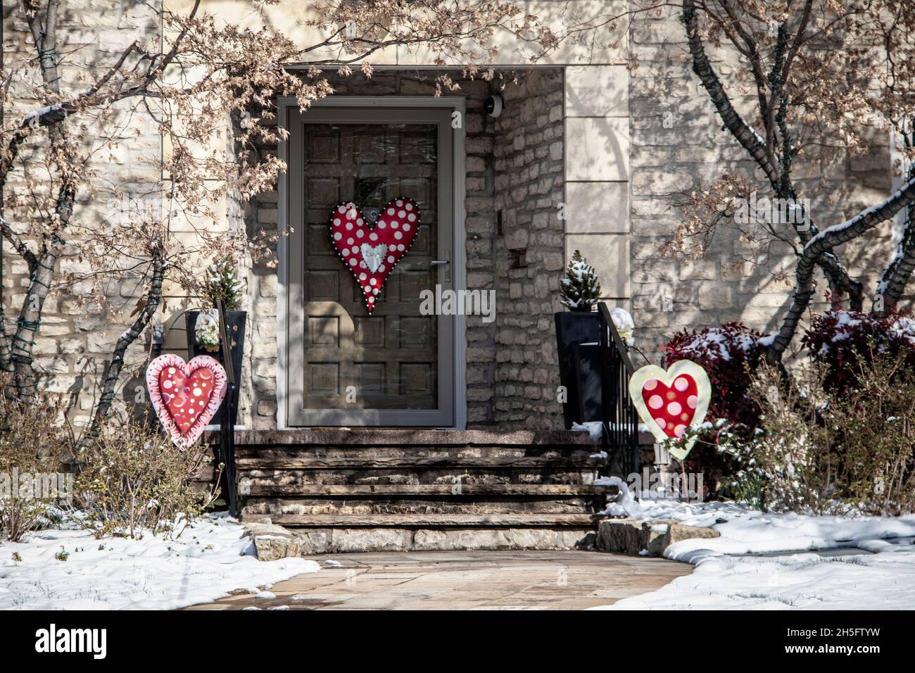 Moderner Steinhaus Eingang und Veranda im Schnee mit valentimes Dekorationen und Landschaftsgestaltung - selektive Farbe Stockfoto