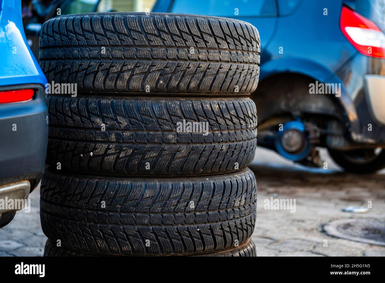 Winterreifen neben dem Auto im Radservice, saisonales Reifenwechselkonzept, Nahaufnahme Stockfoto