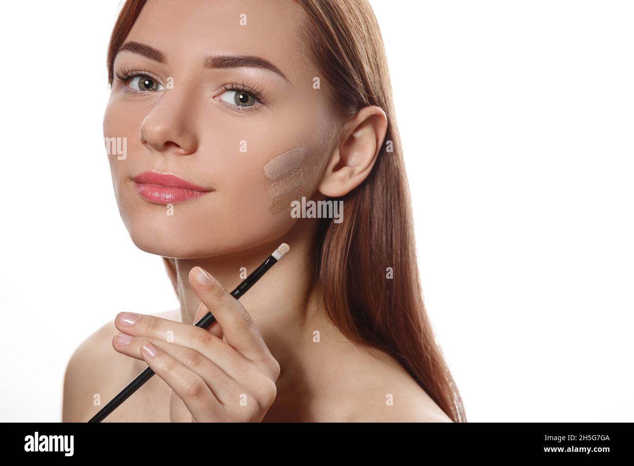 Nahaufnahme Porträt eines jungen Mädchens, das eine Schattierung von Fundament als Basis für Make-up wählt Stockfoto